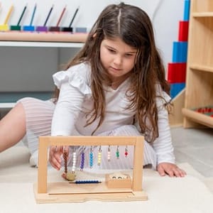 הכרת המספרים וחשבון - ילדה משחקת עם עזר מונטסורי ללימוד מספרים עד 10