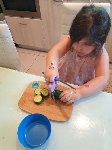 ילדה חותכת מלפפון